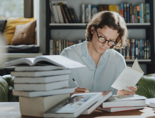山積みの本で勉強する人